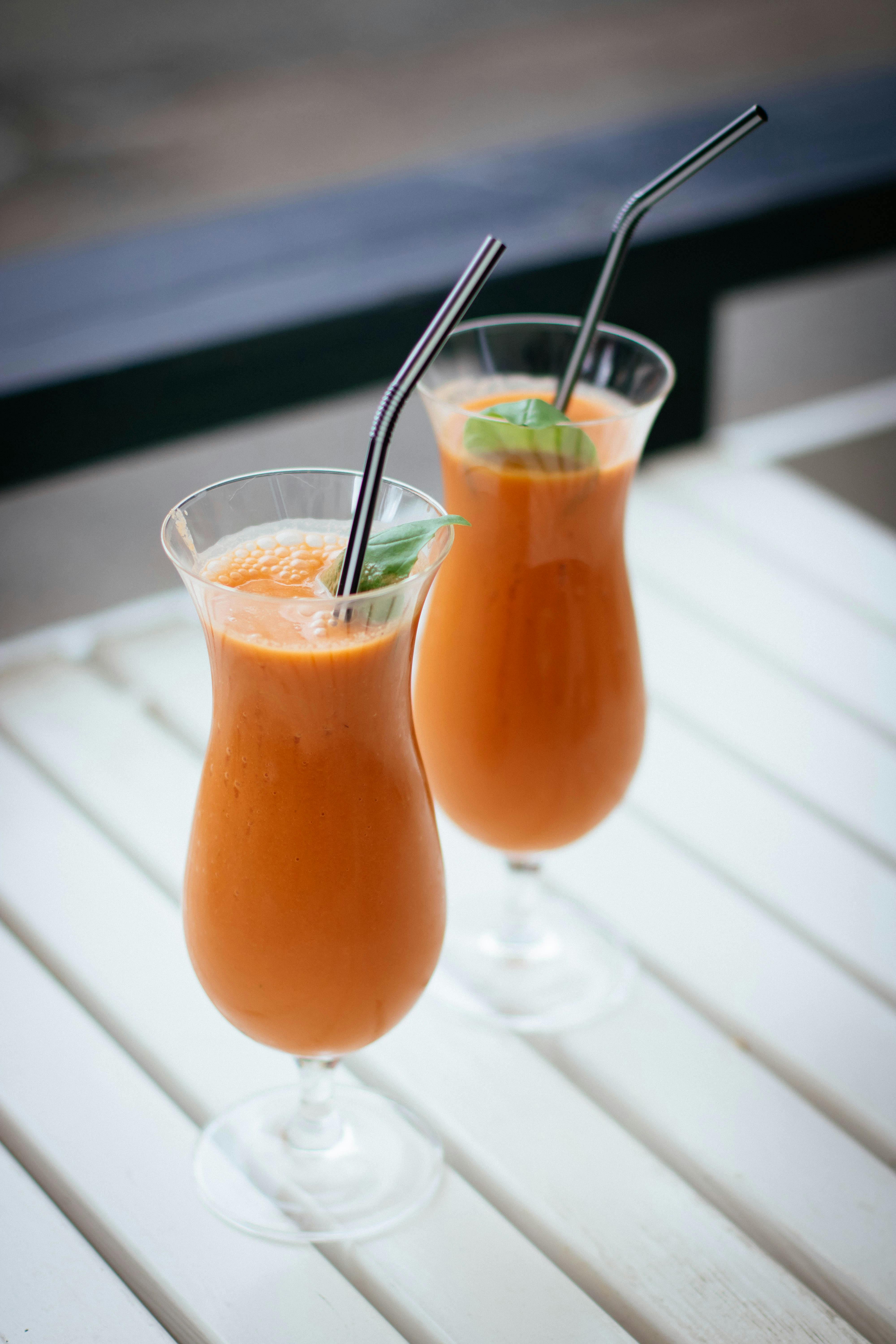 Sweet potato juice in a pair of glasses with straws, ready to drink.